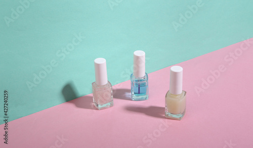 Nail pilish bottles on blue-pink background. Minimalism. Trendy shadow. Creative layout. Beauty still life