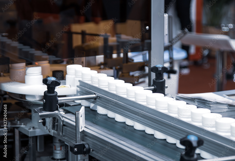 White plastic bottle on capsule filling machine conveyor belt in production line. Pharmaceutical industry
White plastic bottle on capsule filling machine conveyor belt in production line. Pharmaceutical industry