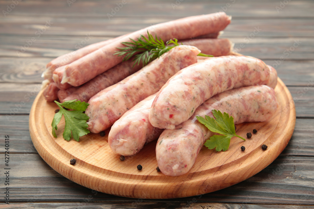 Raw sausage on cutting board on brown background. Top view Raw sausage on cutting board on brown background. Top view