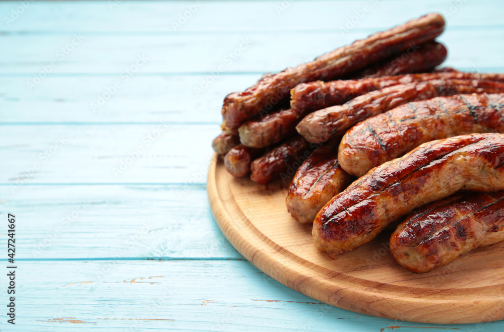 Grilled sausages on wooden board on blue background with copy space