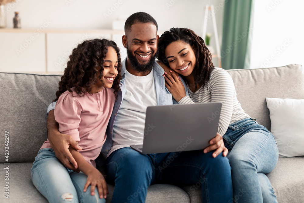 Happy afro family using laptop sitting on the couch