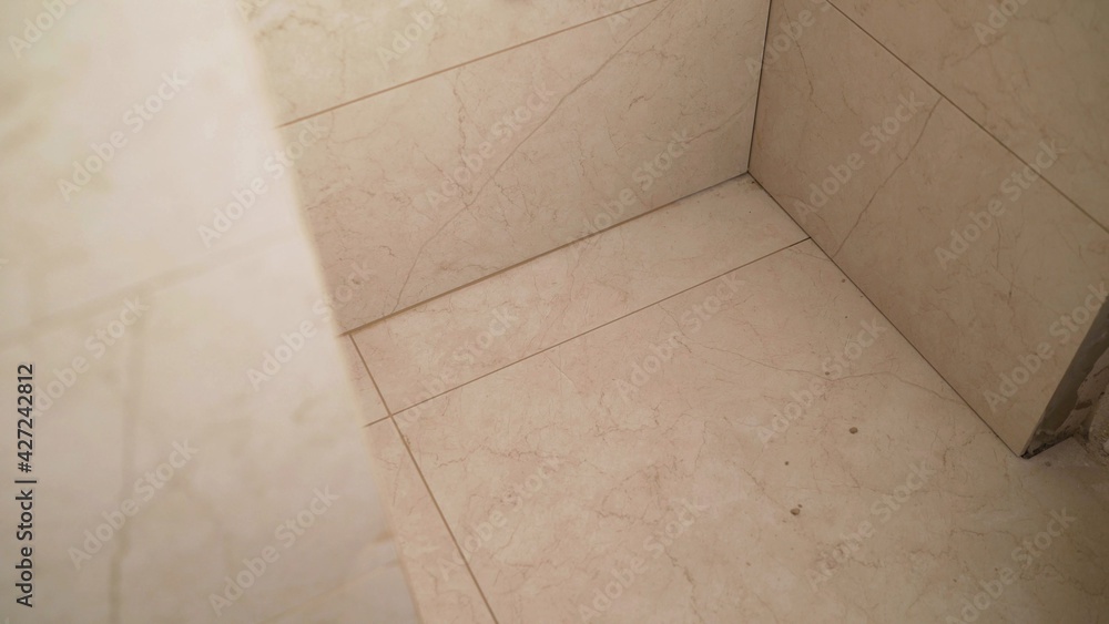 Tile series:Tile border being installed on shower wall in home. Ceramic Floor Tile Application. Bathroom tiles, installation.