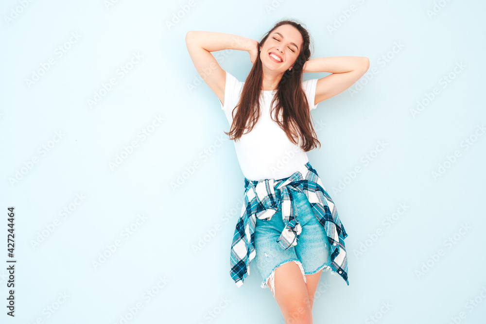 Young beautiful smiling female in trendy summer hipster clothes. Sexy carefree woman posing near light blue wall in studio. Positive model having fun indoors. Cheerful and happy Young beautiful smiling female in trendy summer hipster clothes. Sexy carefree woman posing near light blue wall in studio. Positive model having fun indoors. Cheerful and happy