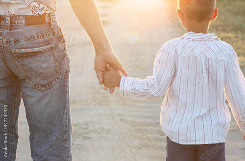 A Hands of a happy child and parent in nature in a park by the road photo