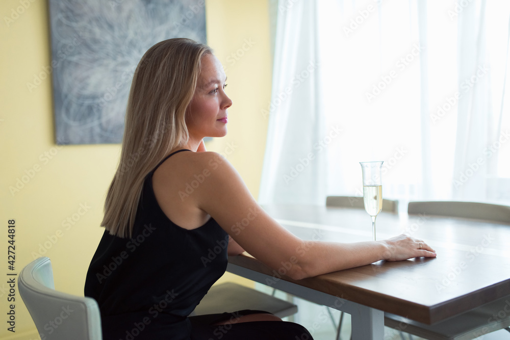 woman sitting at table at home with wine glass