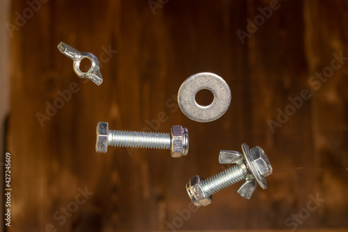falling screws, washer and retaining nut on blurred brown background