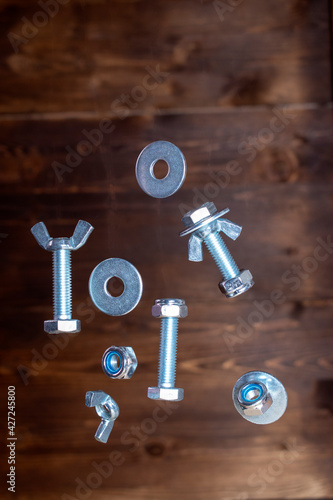 falling screws, washers and nuts on a dark brown background