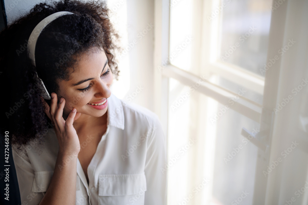 Portrait of young woman with headphones indoors at home, listening to music. Portrait of young woman with headphones indoors at home, listening to music.