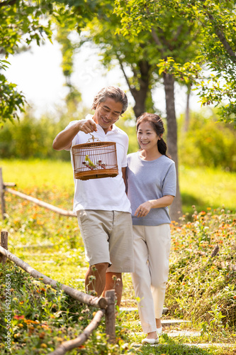 Happy mature couple strolling in park with a birdcage photo