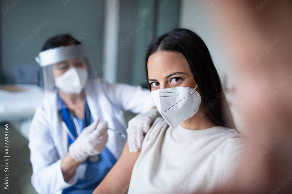 Woman with face mask getting vaccinated and taking selfie in hospital, coronavirus and vaccination concept.