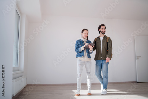 Young couple with tablet moving and planning in new flat, new home and relocation concept.