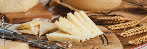 Pieces of  fresh homemade cheese on a wooden board with a knife close up