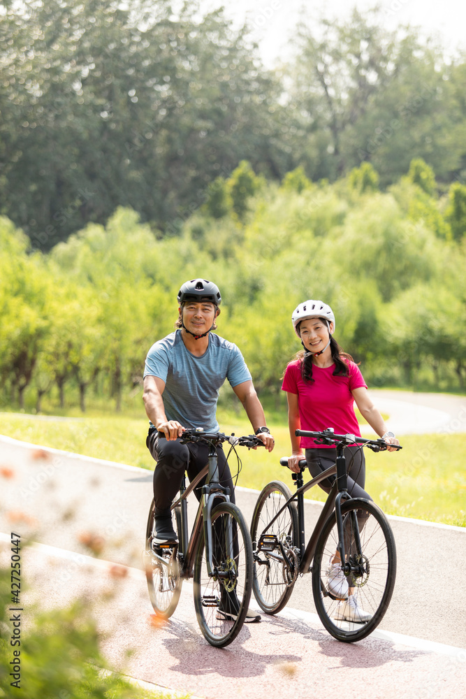 Happy mature couple riding bikes in park Happy mature couple riding bikes in park