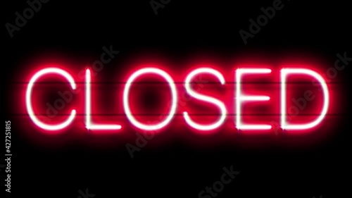 Closed neon sign appear on black background.