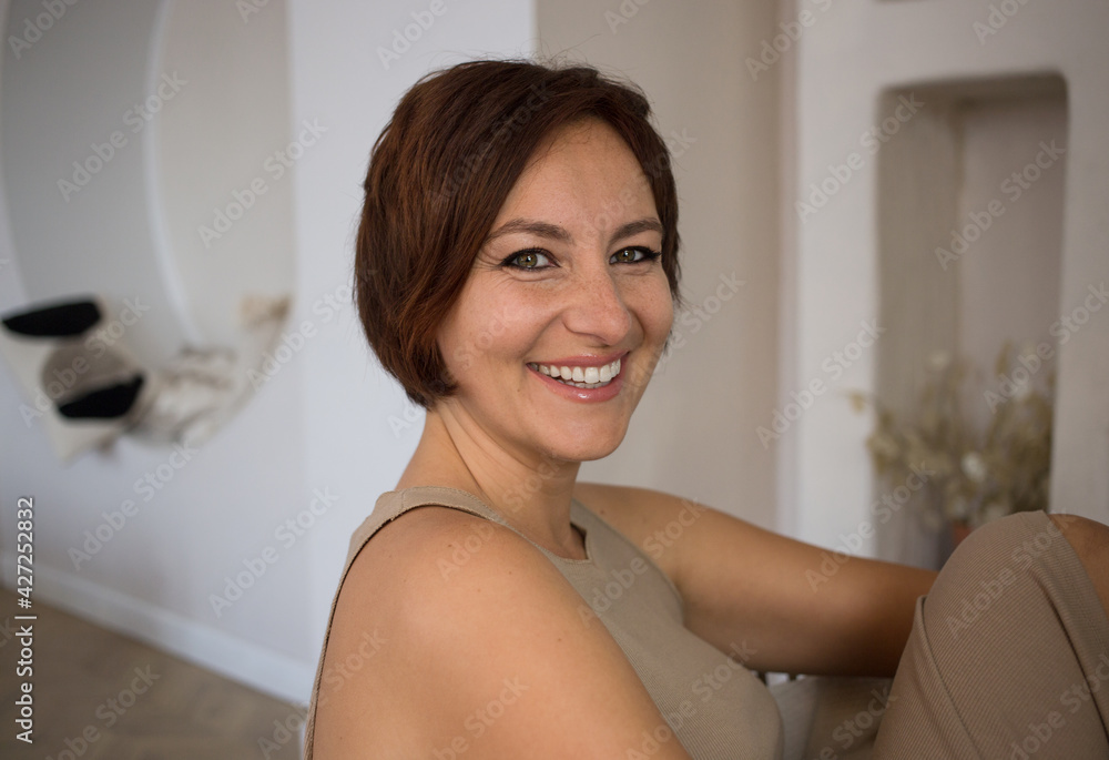 Portrait of a beautiful woman over 30, she smiles with white teeth and looks into the camera. Confident happy adult girl - businesswoman in the room Portrait of a beautiful woman over 30, she smiles with white teeth and looks into the camera. Confident happy adult girl - businesswoman in the room