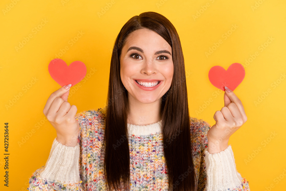 Photo portrait of brunette woman showing red hearts smiling isolated on bright yellow color background Photo portrait of brunette woman showing red hearts smiling isolated on bright yellow color background