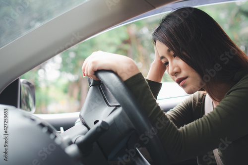 Stressed and unhappy Asian woman driver sitting inside her vehicle and feeling sad and angry. Car accidents are caused by negligence. And the driver tired. Drunk and Sleepy female hangover.