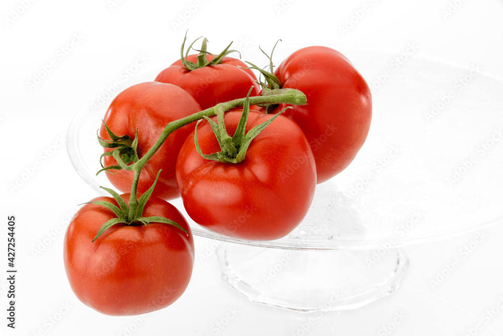 tomatoes isolated on clear glass raised plate isolated on white background. copy space tomatoes isolated on clear glass raised plate isolated on white background. copy space