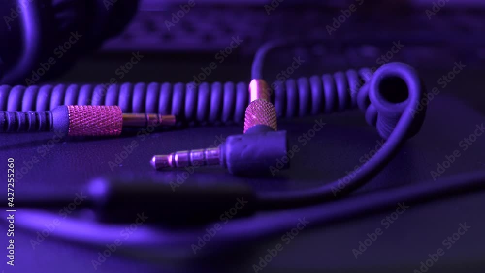 Loose audio jacks and wires on table lit by party lighting with changing colours. Pedestal shot. Loose audio jacks and wires on table lit by party lighting with changing colours. Pedestal shot.
