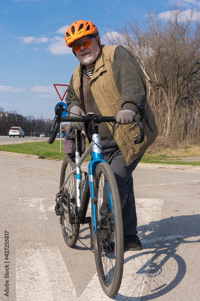 Outdoor portrait of a bearded, chubby senior man getting ready to ride on gravel bicycle Outdoor portrait of a bearded, chubby senior man getting ready to ride on gravel bicycle