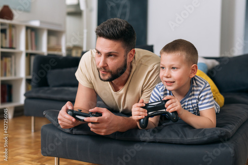 father playing video games with his son. they are sitting in living room