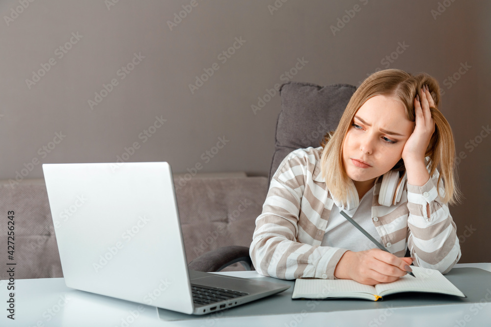 Unhappy teen girl during home online education using laptop. Stress sadness female student do homework classes. Sad woman work remote from home. Unhappy teen girl during home online education using laptop. Stress sadness female student do homework classes. Sad woman work remote from home.