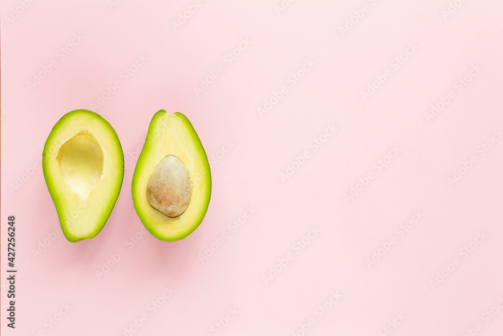 Two halfs of avocado with and without seed on pink background. Top view. Two halfs of avocado with and without seed on pink background. Top view.
