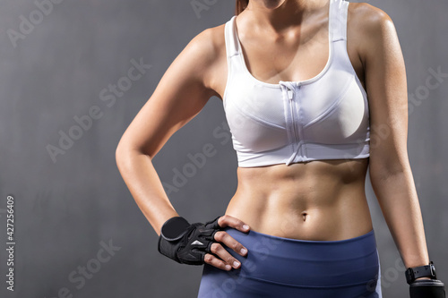 Sexy Asian Woman Abdominal with Six Pack Core Body Muscle Against Dark Background