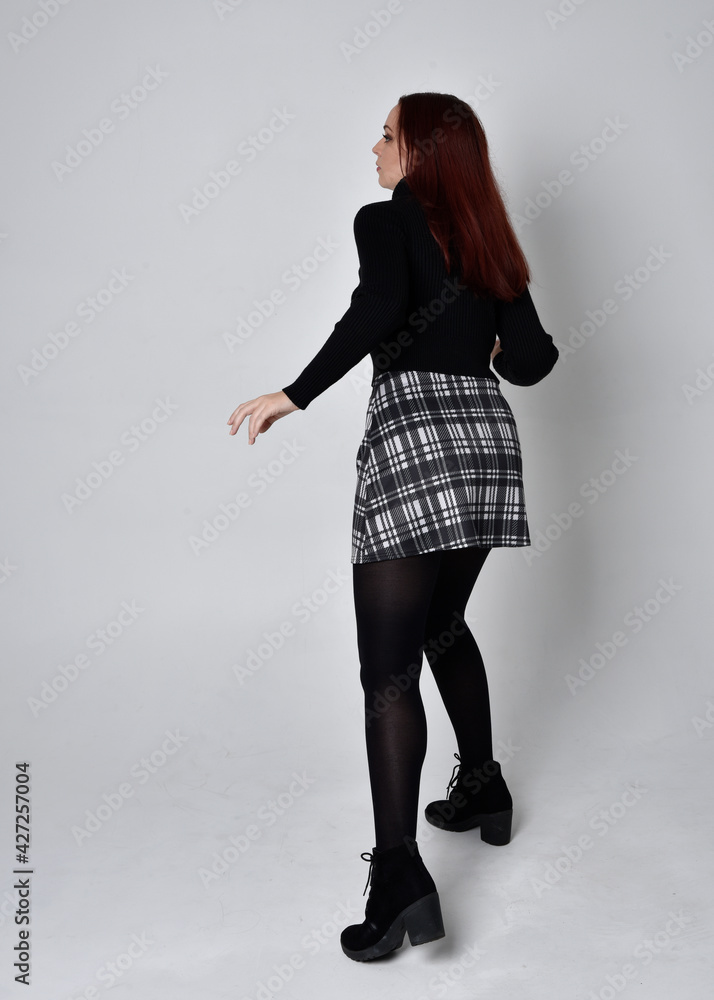 Full length portrait of a red haired girl wearing black turtleneck ...