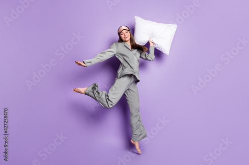 Full length body size view of lovely trendy glad cheery girl holding pillow jumping having fun isolated on violet purple color background