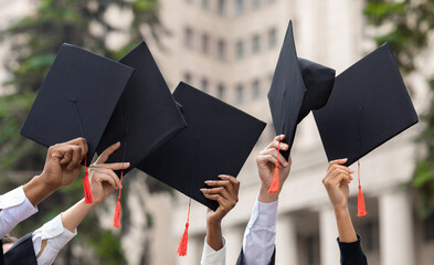 Cropped of students raising up hands with caps