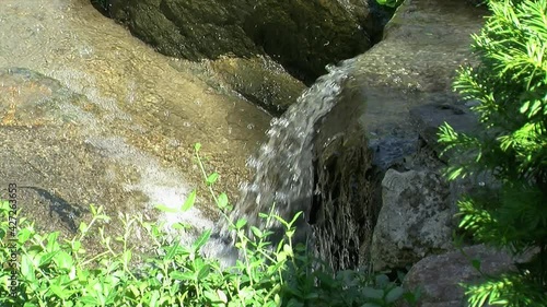 Cascade of water flows over the brink of a small waterfall, then downstream. photo