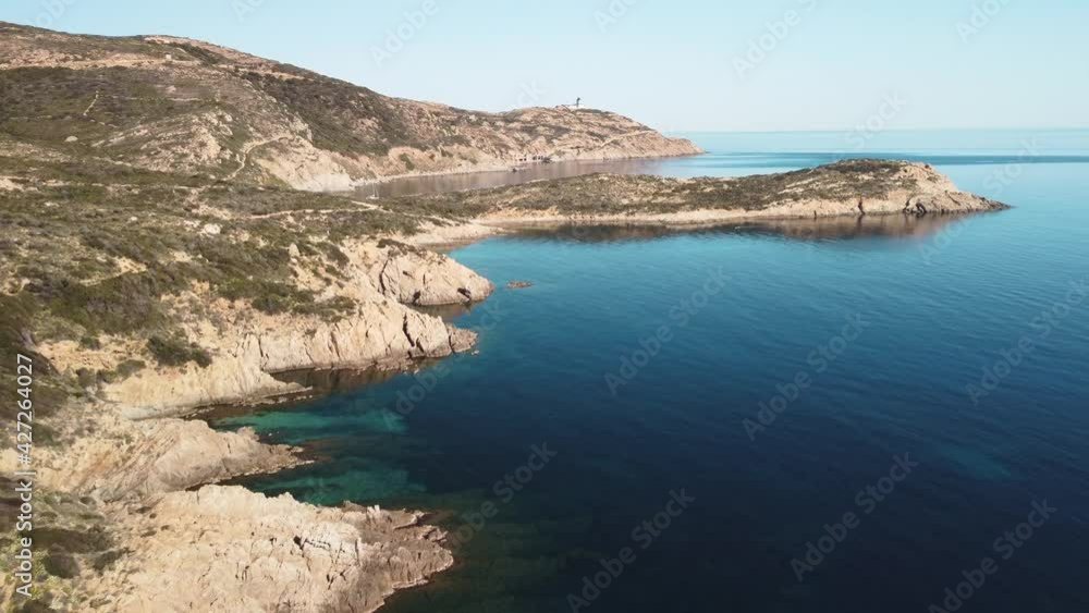 Aerial view of the rocky coastline and turquoise Mediterranean sea of La Revellata near Calvi in the Balagne region of Corsica as a kayak paddles around a shallow bay with a lighthouse in the distance Aerial view of the rocky coastline and turquoise Mediterranean sea of La Revellata near Calvi in the Balagne region of Corsica as a kayak paddles around a shallow bay with a lighthouse in the distance