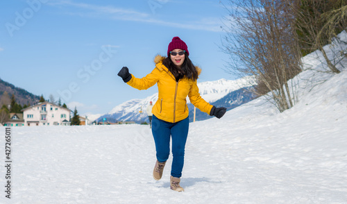Winter holiday trip to snow valley - young happy and excited Asian Korean woman running playful on frozen lake in snowy mountains at Swiss Alps enjoying