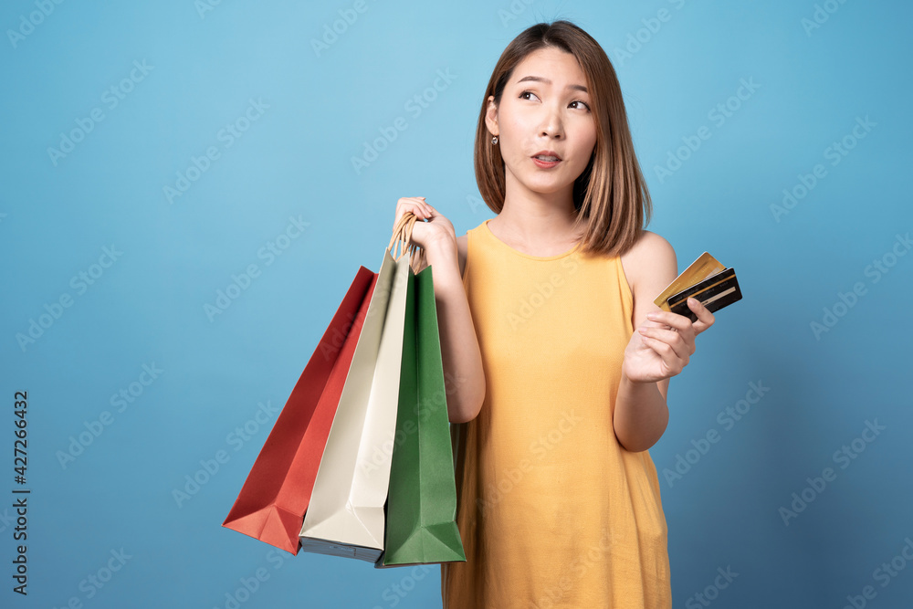 Young asian woman carrying shopping bags and credit card, Isolated on blue background. Young asian woman carrying shopping bags and credit card, Isolated on blue background.