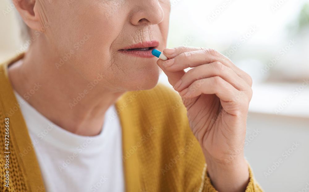 Cropped of senior woman with glass taking medicine Cropped of senior woman with glass taking medicine