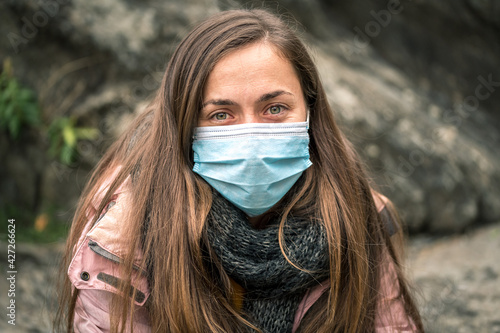 Portrait of a green-eyed Caucasian girl with a surgical mask