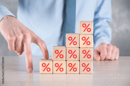 Businessman hand takes a wooden cube block depicting,shown the percentage symbol icon. Interest rate financial and mortgage rates concept.