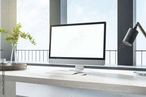 Pc standing on a desk in a bright room with black columns and big windows, white desktop, corner view, workplace and interior design concept, 3d rendering, mock up