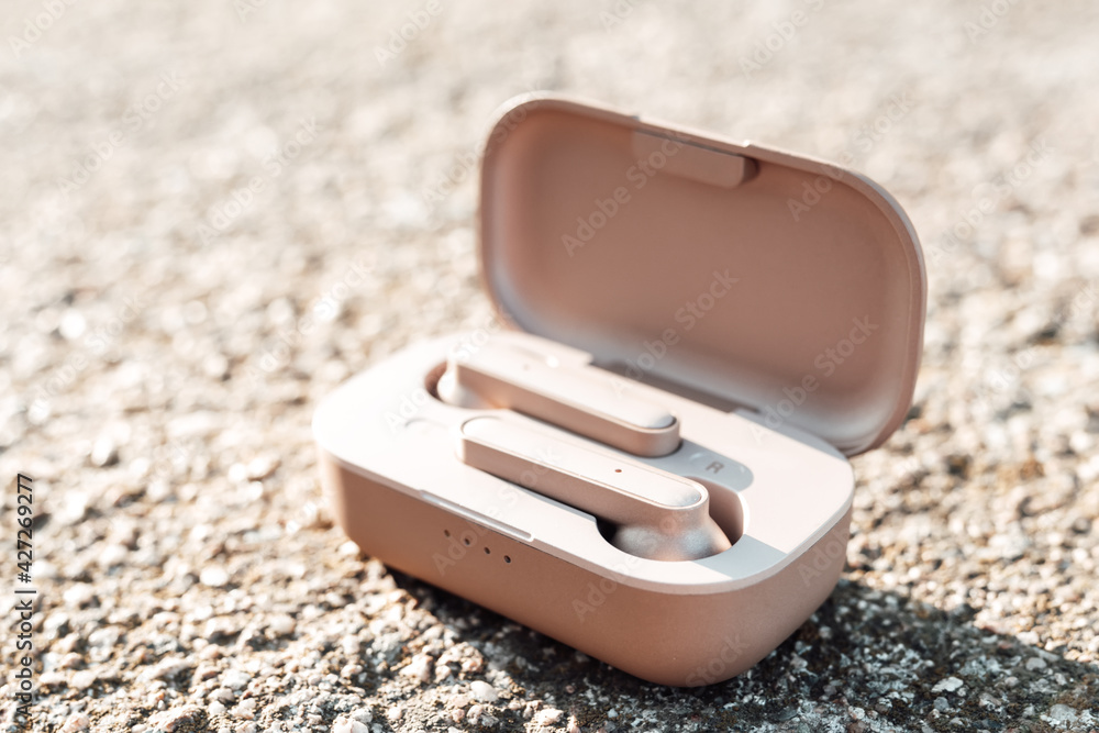 True wireless earbuds in case on natural stone background, top view,closeup, copy space True wireless earbuds in case on natural stone background, top view,closeup, copy space