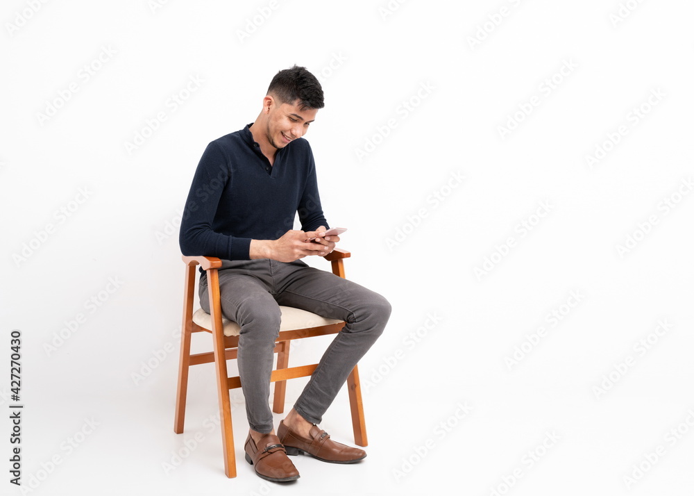 Latin man sitting with mobile phone in hands on white background