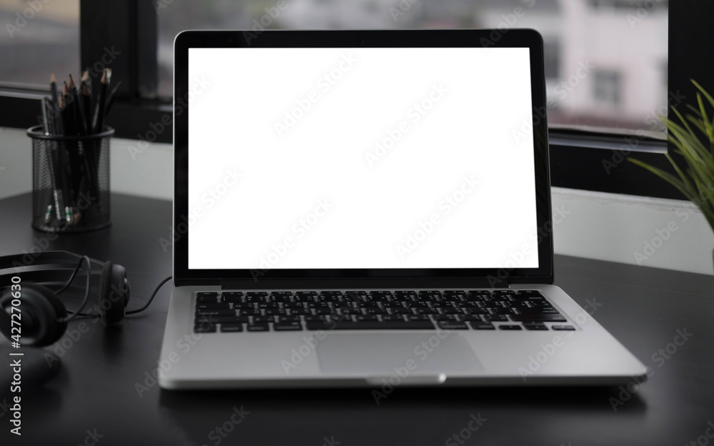 Close-up view of open blank screen laptop computer with office supplies in modern office Close-up view of open blank screen laptop computer with office supplies in modern office