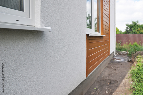 Modern house facade insulation under plastering, stucco and wood wall siding. The combination of stucco and wood siding, wood cladding on the external house wall. photo