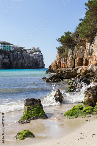 Beautiful sunny day at the beach with crystal clear turquoise water surrounded by cliffs. Cala en Porter, Menorca.