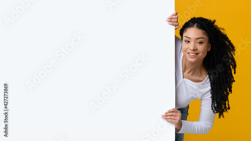 Positive Black Lady Peeking Out Of Blank White Advertisement Board