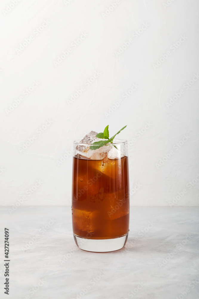 Cold fruit tea with ice in a tall glass. Summer refreshing soft drink. Light background, vertical orientation, copy space Cold fruit tea with ice in a tall glass. Summer refreshing soft drink. Light background, vertical orientation, copy space