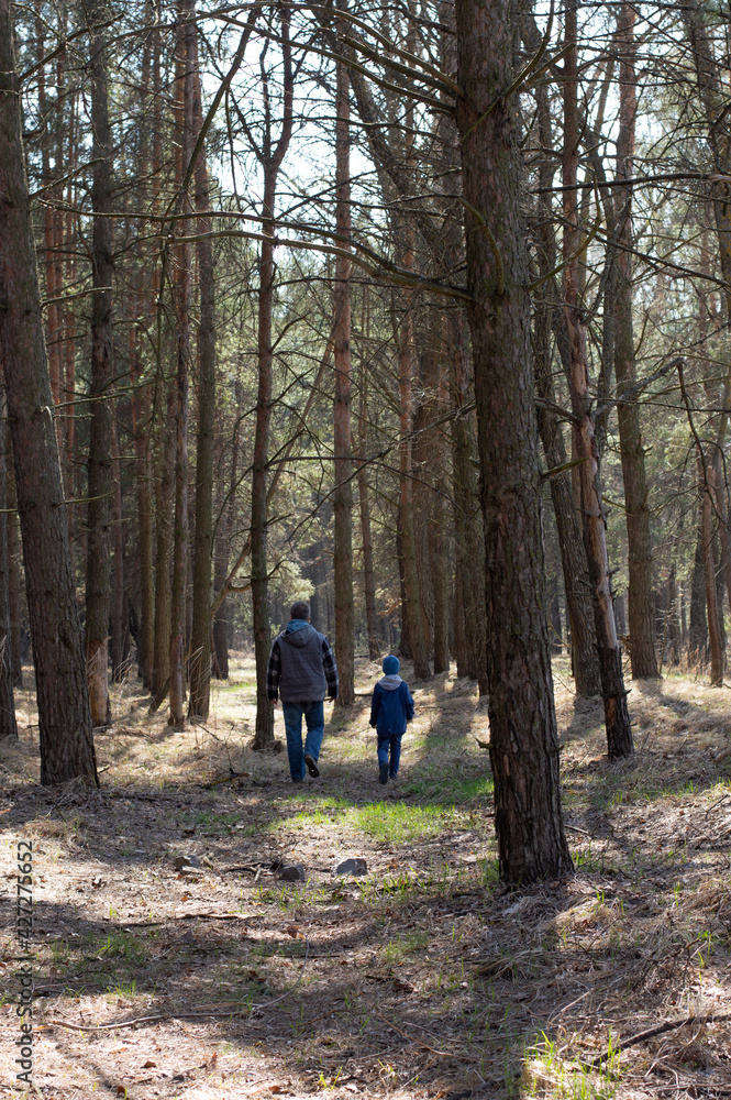 Blurred image of a boy with his father walking through the forest in early spring.