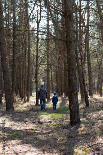 Blurred image of a boy with his father walking through the forest in early spring.