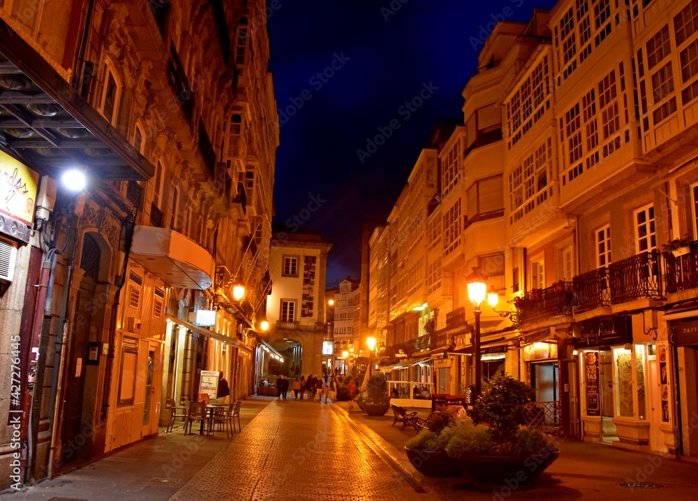 Imagen nocturna de una calle peatonal en verano con la atmósfera cálida que le confiere la iluminación artificial