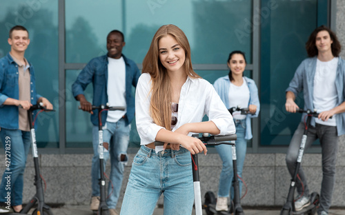 Woman having ride on motorized kick scooter with friends